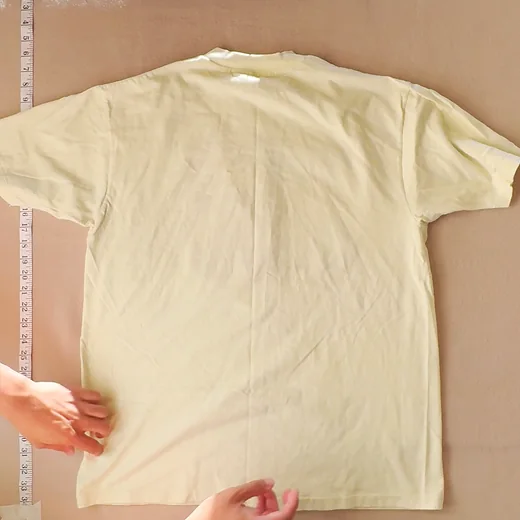 Grid tile of the raw back photo: sleeves clipped at both edges, hands and tapes in frame.